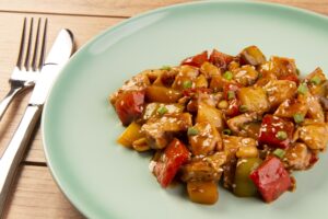 chess chicken in green dish on wooden background - chinese food.
