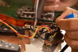luthier soldering a guitar wire in his workshop